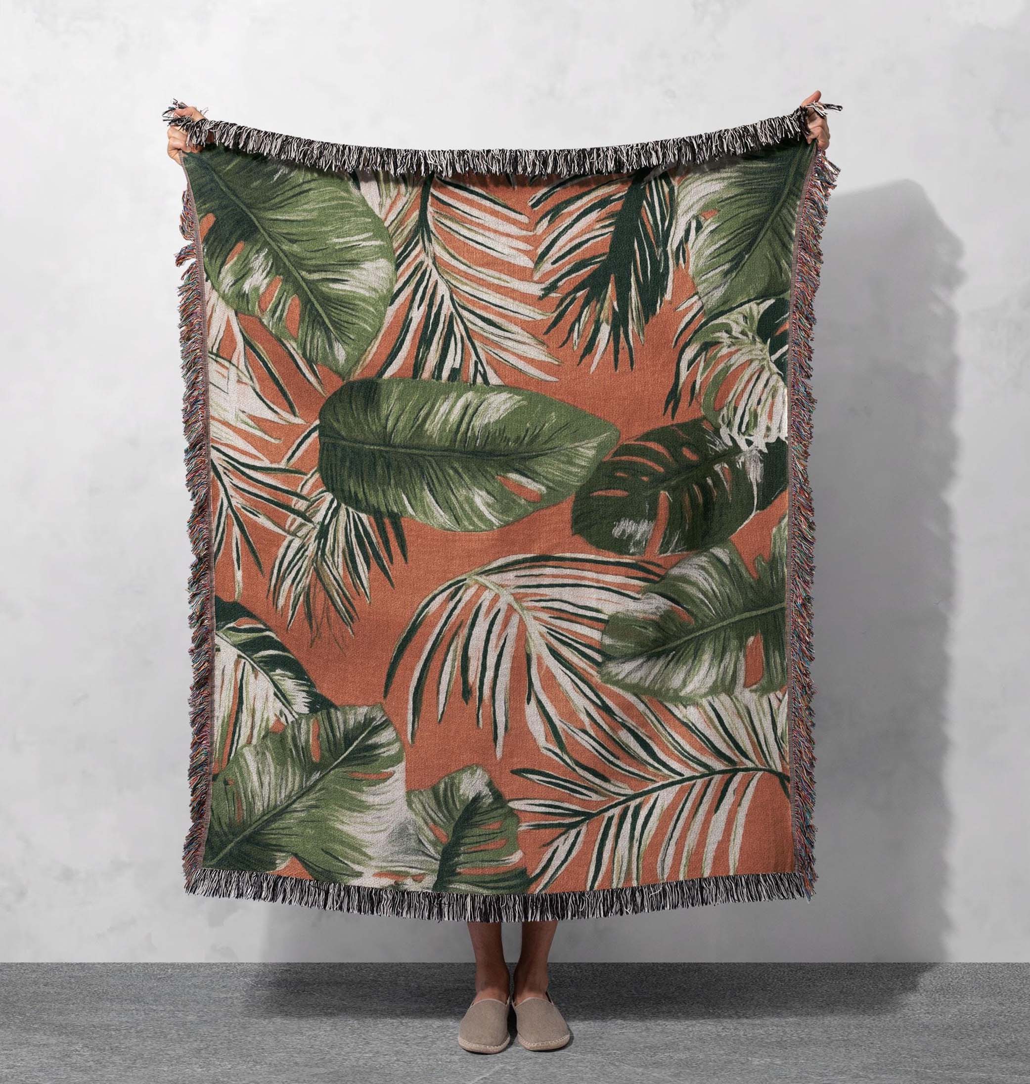 tropical leaf woven blanket bold green leaves on warm earthy background with fringed edges cottagecore tapestry